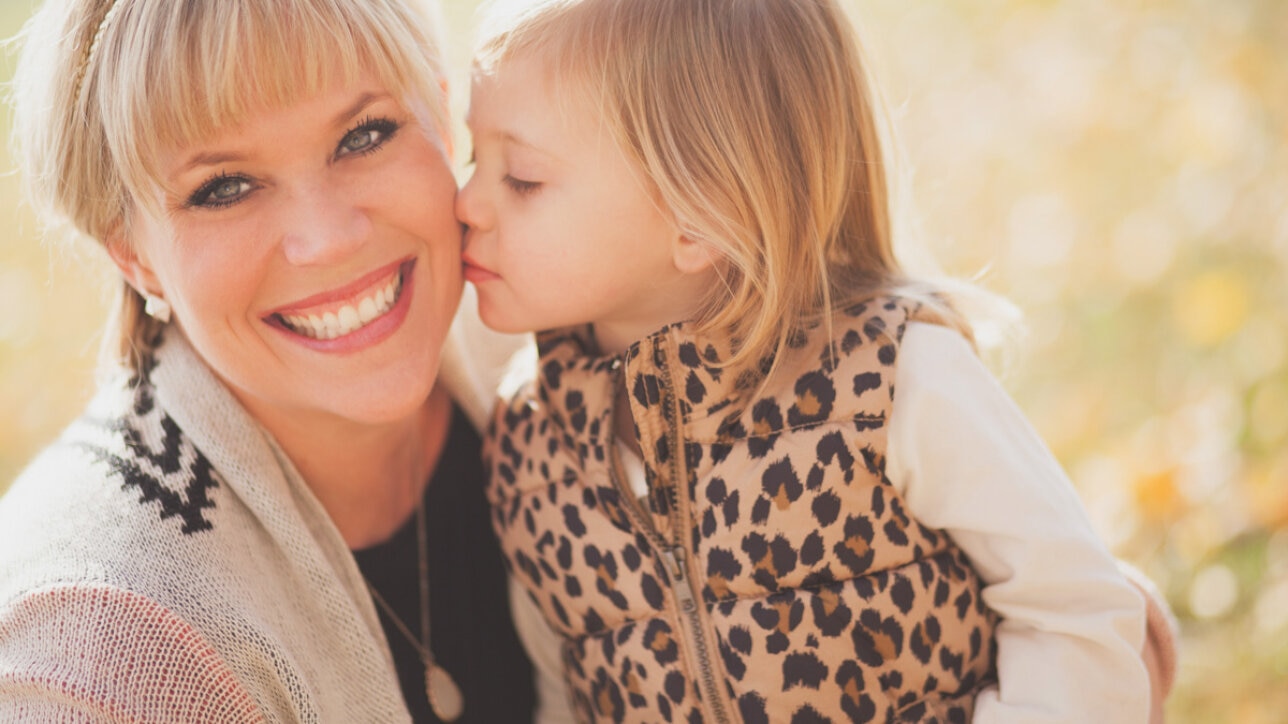 girl kissing woman on cheek